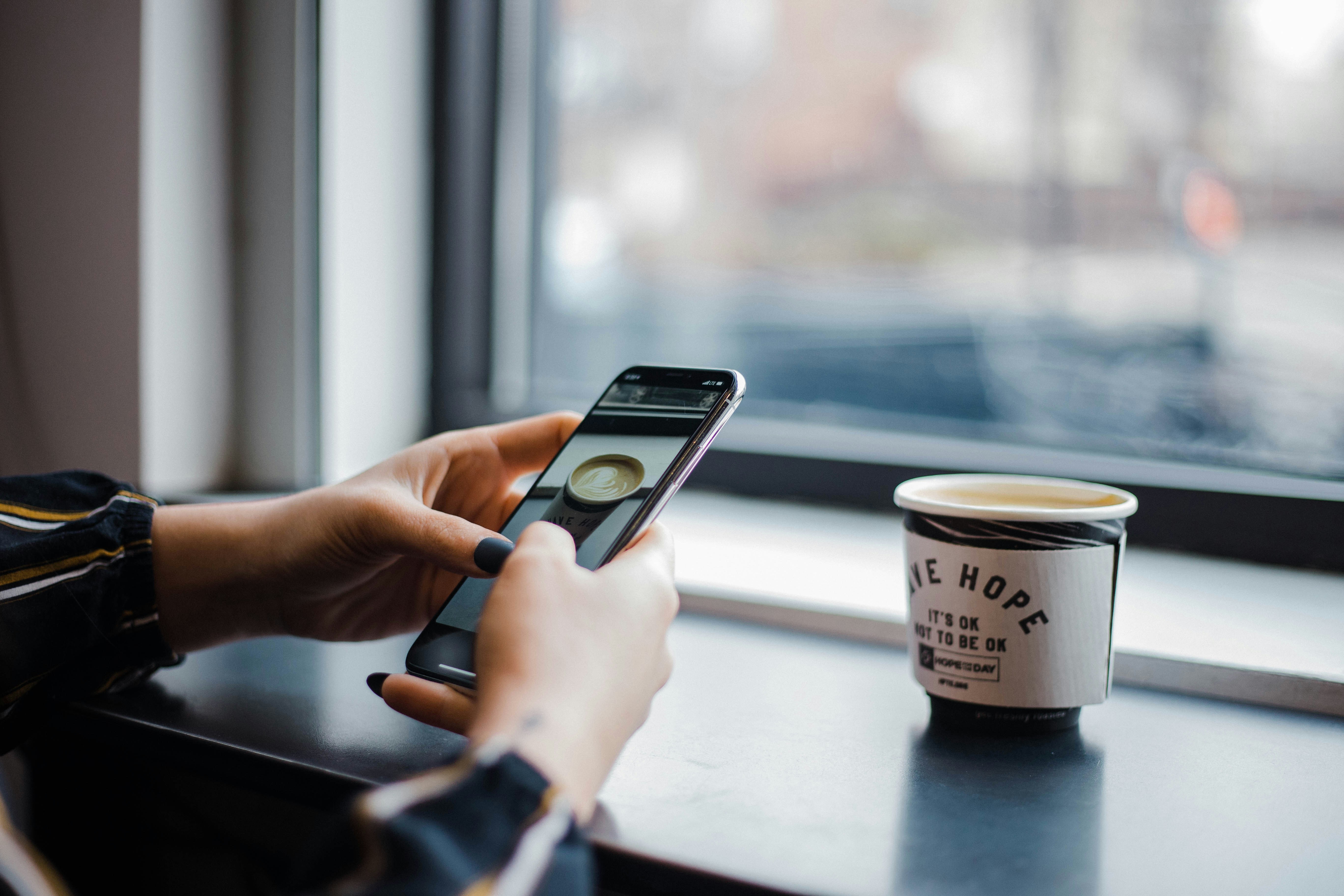 Person using an older iPhone model confidently in a coffee shop