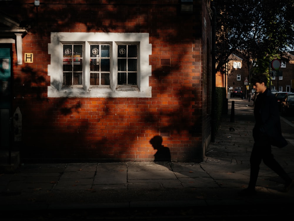 man walk beside wall during daytime