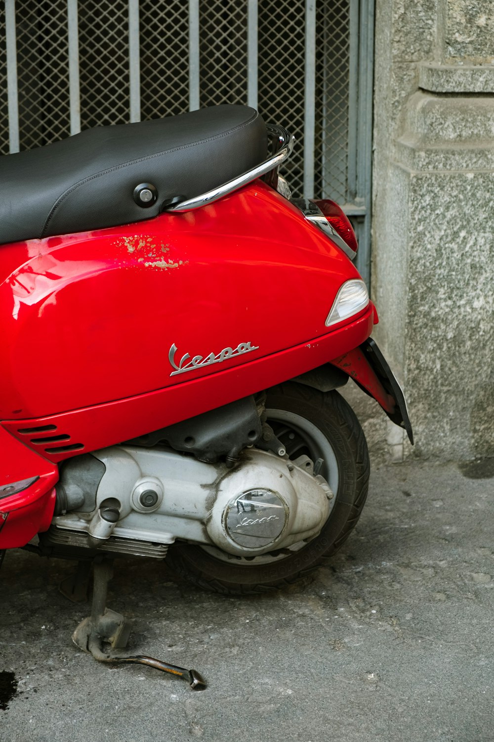 red Vespa motor scooter parked near gate