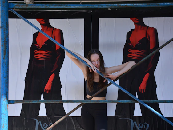 A striking black and pink graphic of a woman behind stylized prison bars, with barbed wire subtly woven into the background.