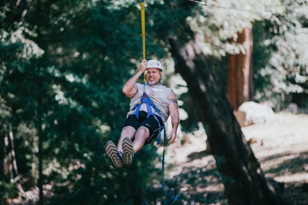 man hanging and wearing harness during daytime