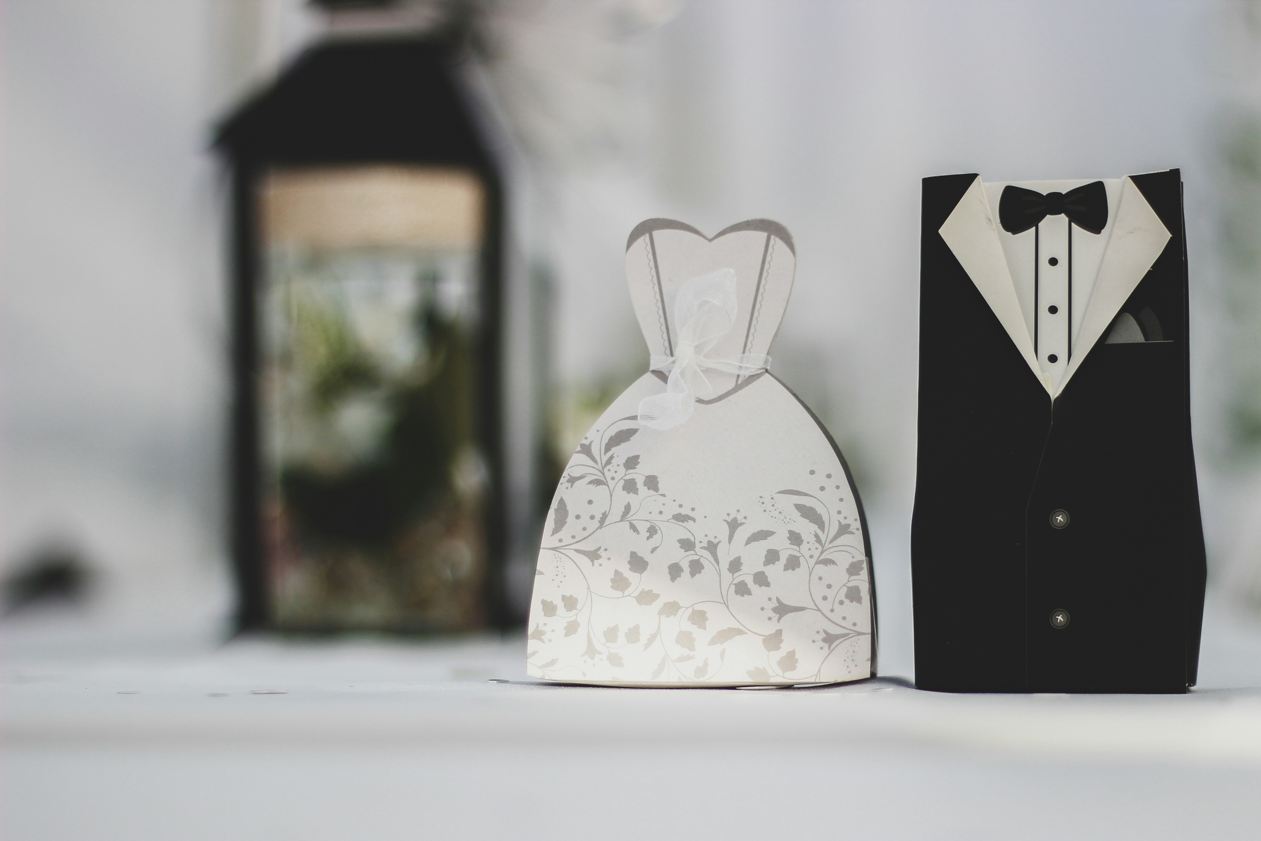 Two small wedding favor boxes shaped like a dress and tuxedo.