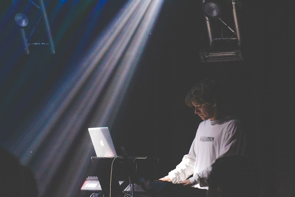 man in white sweater playing electronic keyboard