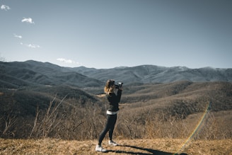 Barry Bailey standing with his camera in a sunlit mountain meadow in Fort Collins.