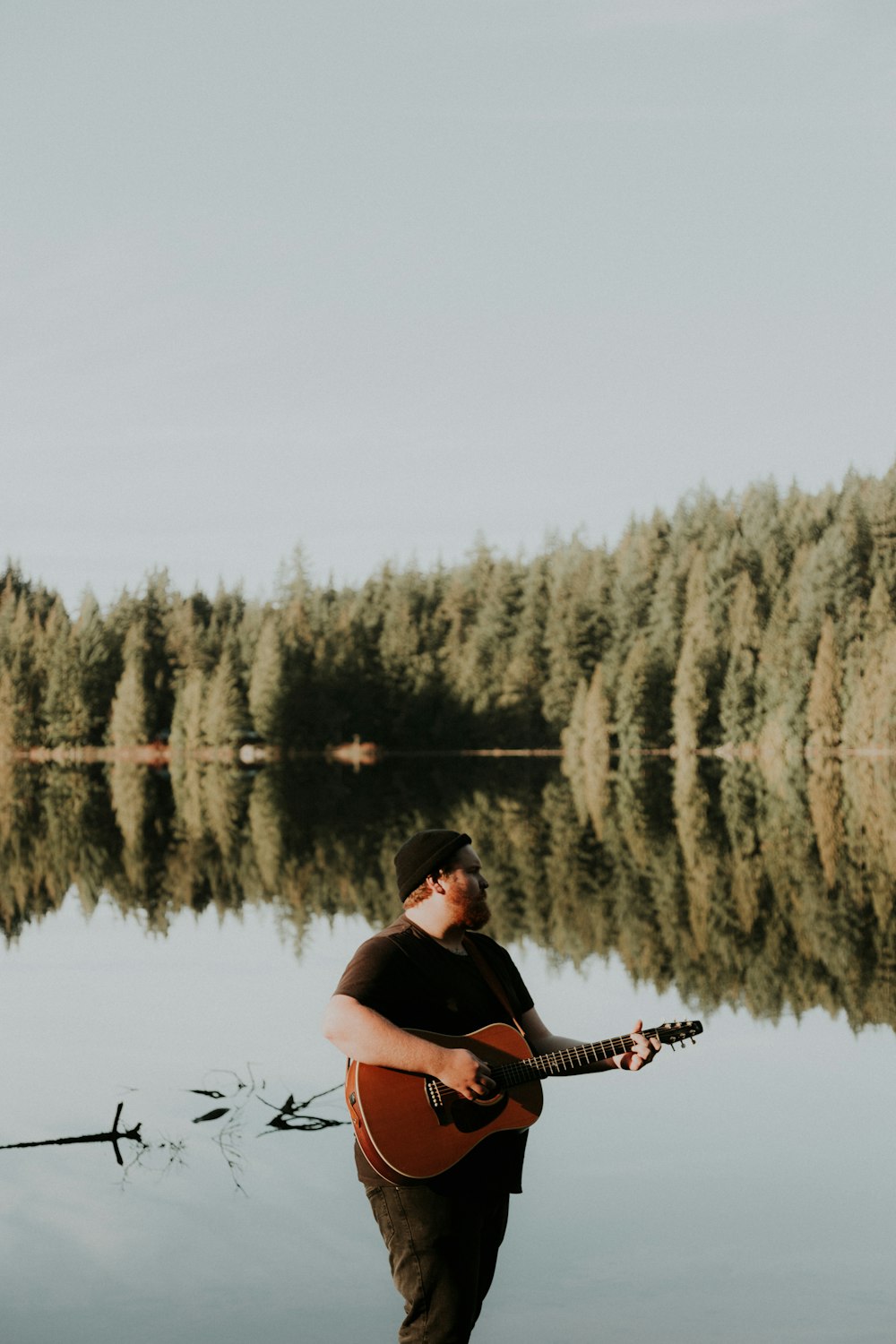 man half soak in body of water playing guitar