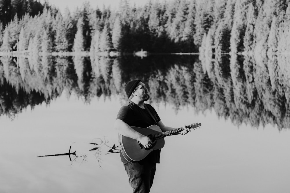 grayscale photo of man playing acoustic guitar