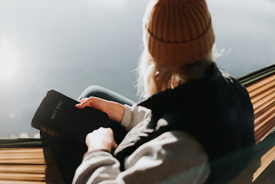 A peaceful scene showing a person wearing a faith-themed hoodie while reading scripture outdoors.