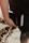 A person is holding a black book labeled 'Holy Bible' in their hand. The image captures a close-up view of the book and hand, with a blurred outdoor background.