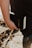 A person is holding a black book labeled 'Holy Bible' in their hand. The image captures a close-up view of the book and hand, with a blurred outdoor background.