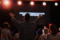 man standing infront of stage lifting hands