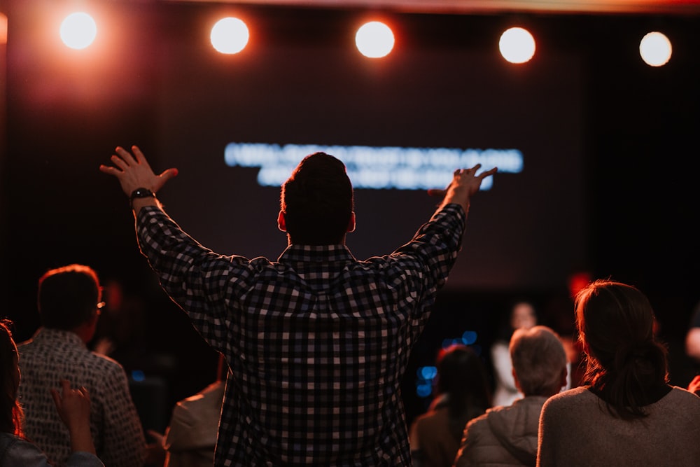 man standing infront of stage lifting hands