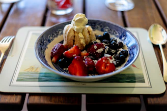 View of a rustic wooden table with bowls of mixed berries and creamy sorbets.