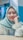 A person wearing a light blue hijab and white blouse, smiling with braces on their teeth. The background is softly blurred with shades of blue and pink.