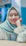Portrait of a smiling Pakistani woman feeling relieved after physiotherapy session in a bright clinic.