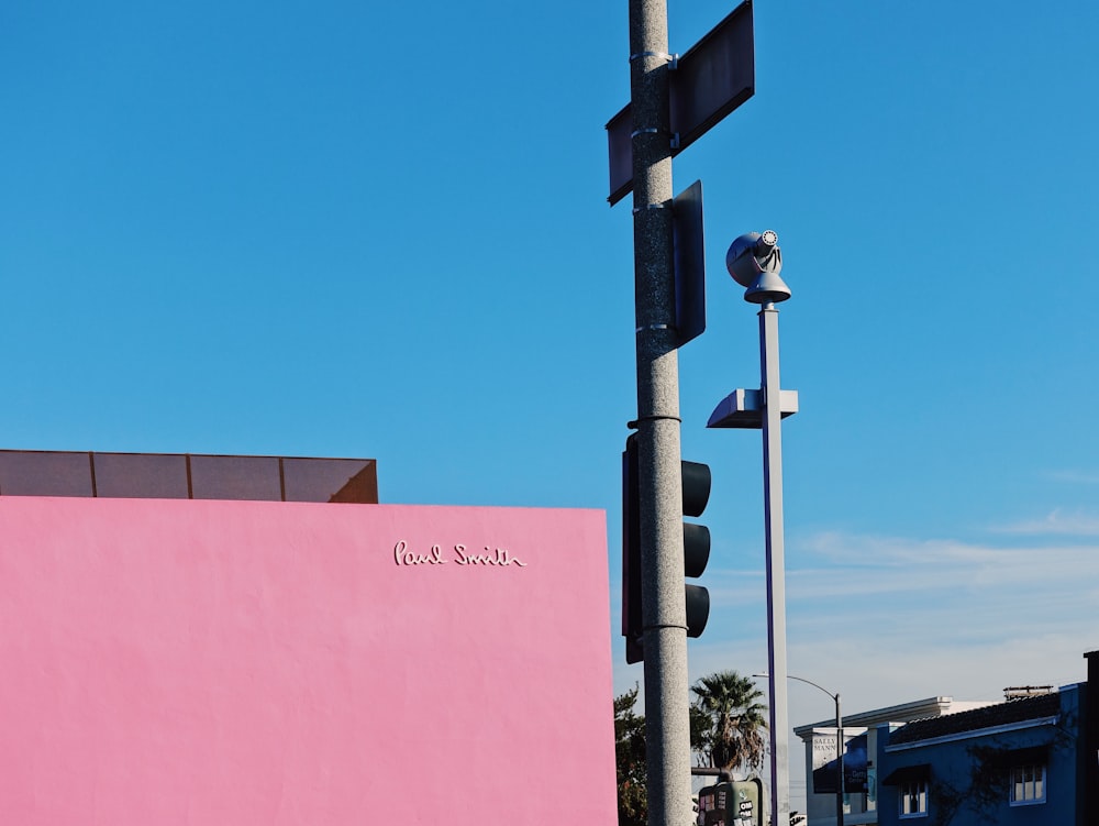 gray metal traffic light near pink painted wall during daytime