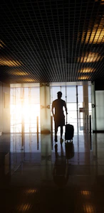 silhouette of man holding luggage inside airport