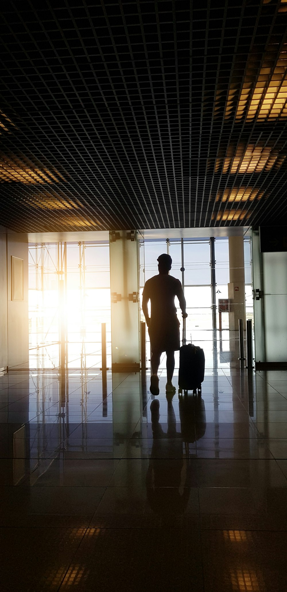 silhouette of man holding luggage inside airport