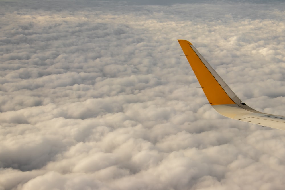 yellow airplane tail on white clouds