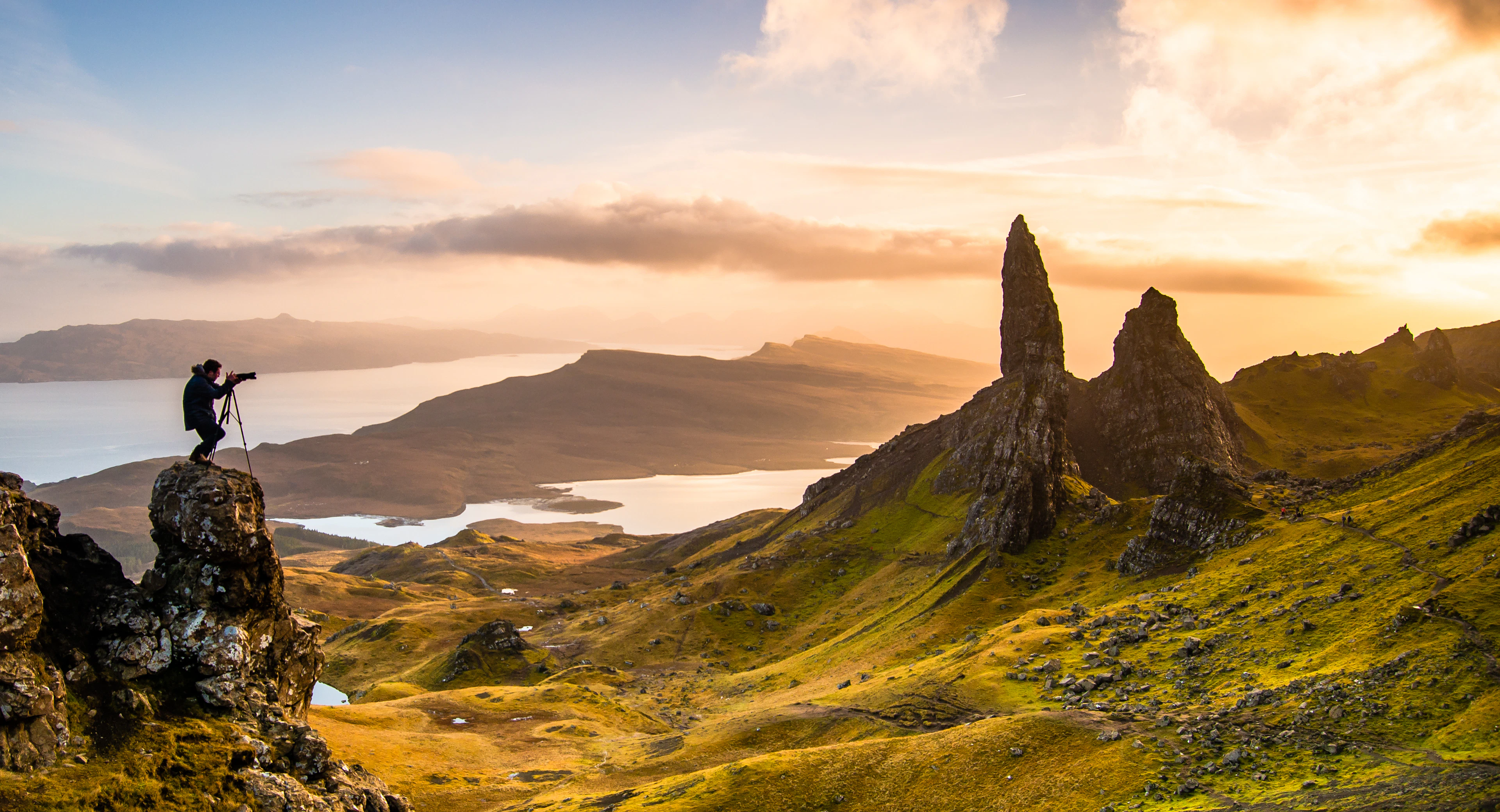 A walker standing on a rock below the Old Man of Storr