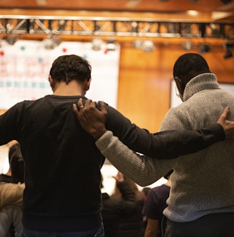 two men holding ear others hand