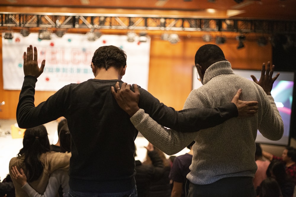 two men holding ear others hand