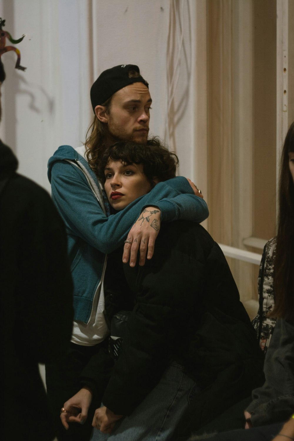 man in blue jacket hugging woman in black jacket