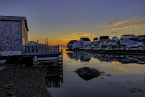 A quiet coastal village at sunset with fishing boats gently rocking on calm waters