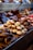 An assortment of beautifully arranged pastries and confections displayed in a bakery setting. The image features cupcakes, donuts, and various chocolates, each decorated with intricate details and toppings. The colors and textures of the sweets create a visually appealing and inviting presentation.