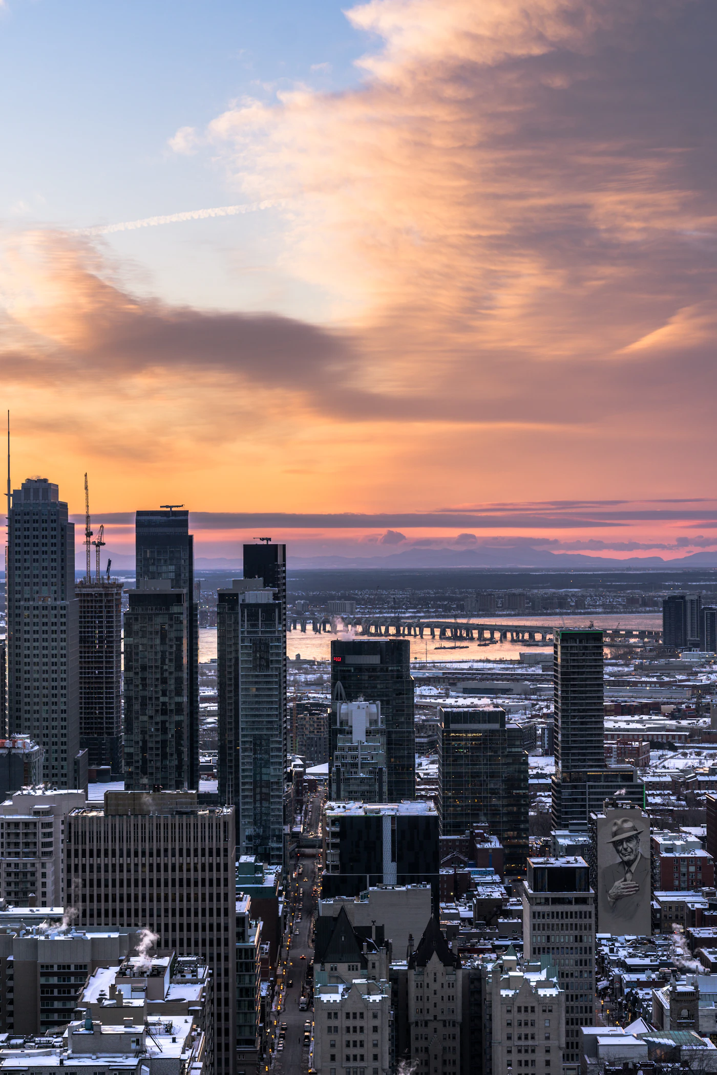 Stone buildings of central Montreal with distant green hills under a clear sky