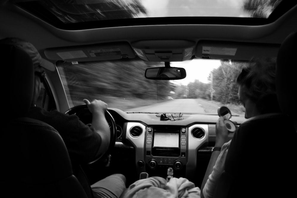 grayscale photography of two persons inside vehicle