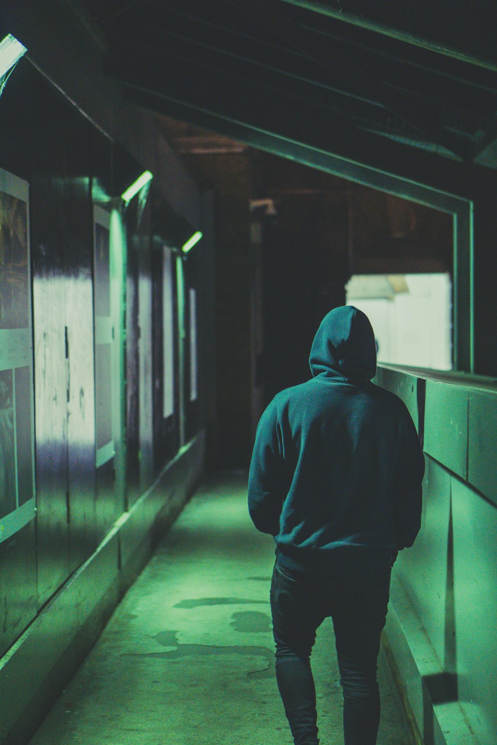 man wearing hoodie walking near wall