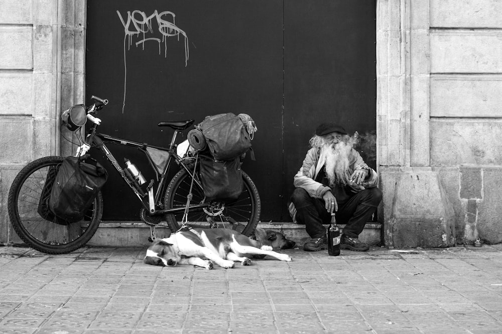 man sitting beside wall and bike