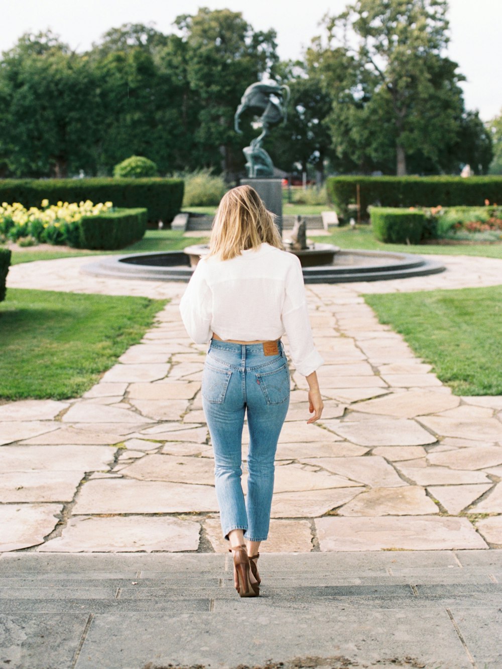 woman walking near black water fountain