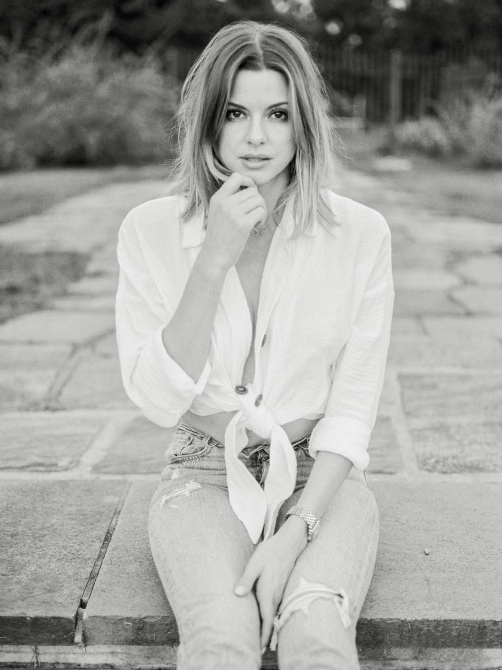 woman sits on pavement in grayscale photo