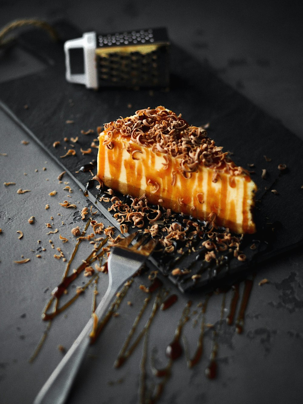 slice of caramel cake on black plate beside fork