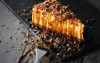 slice of caramel cake on black plate beside fork