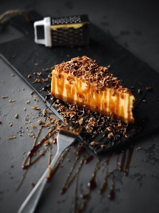 slice of caramel cake on black plate beside fork