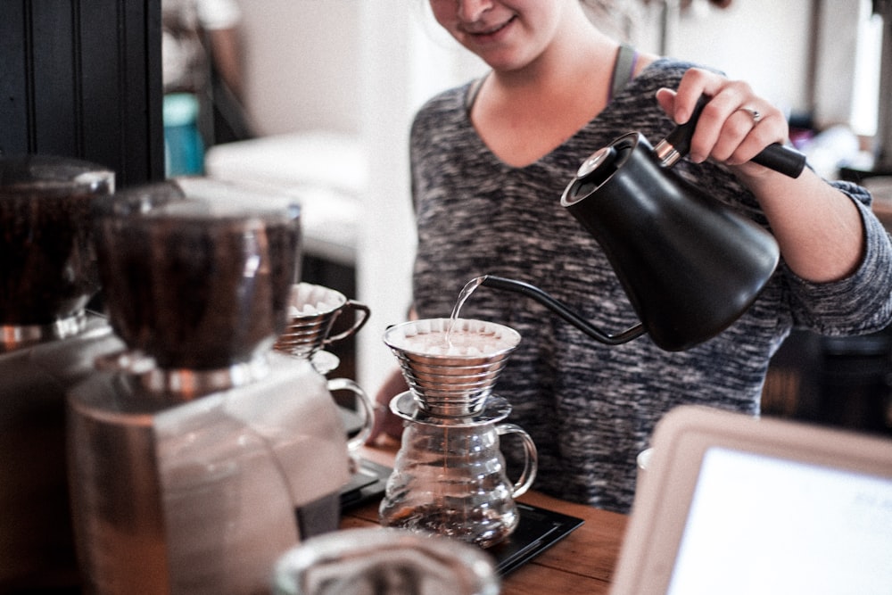 femme versant du thé sur une tasse de thé à l’aide d’une théière