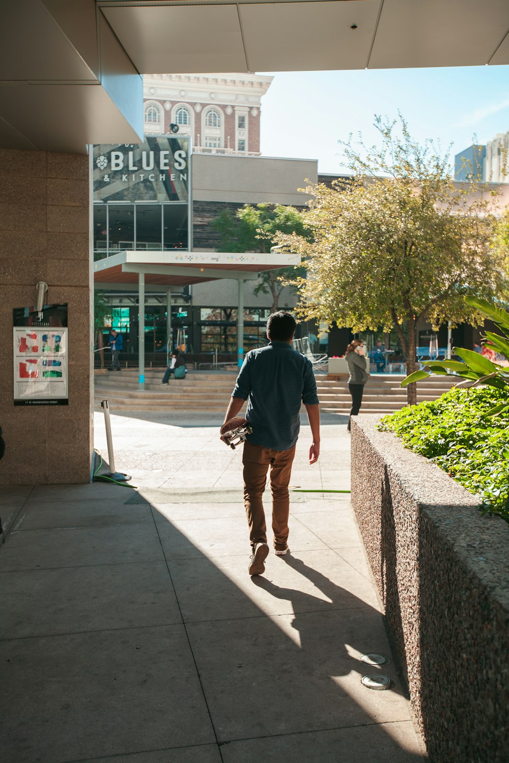 uomo in camicia grigia che cammina dall'edificio durante il giorno