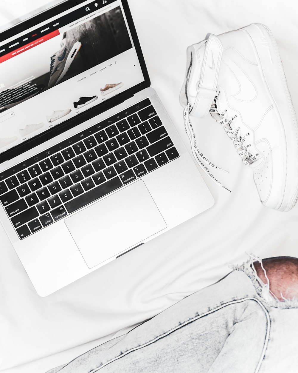 black and white laptop computer near pair of white high-top sneakers