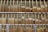 A neatly organized display of cigars in a wooden rack, with various brands and labels visible on the cigars. Each compartment contains an array of cigars, showing diverse shades of brown and different sizes. The setting suggests a retail environment for cigar enthusiasts.