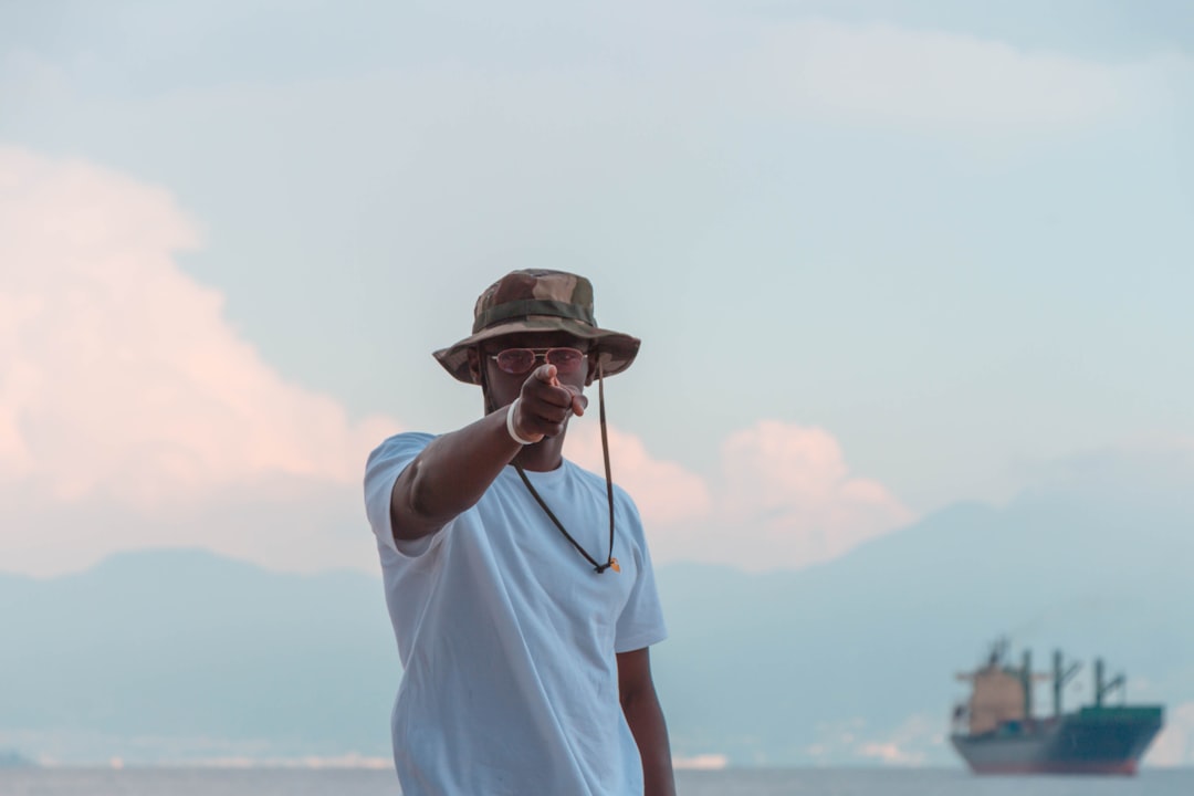 guy pointing with a ship and mountain range in the background
