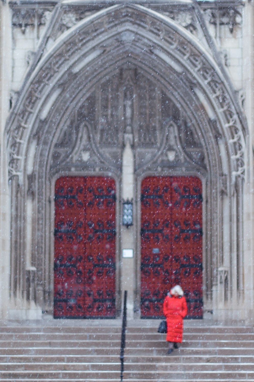 ドアの脇に立つ赤いコートの女性