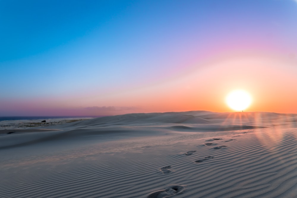 foot prints on sand under clear blue sky