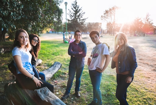 two men and three women near green leaf trees at daytime