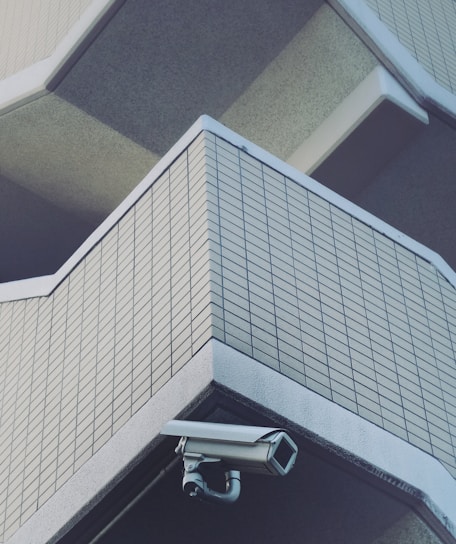 A professional technician installing a CCTV camera on a modern building exterior.