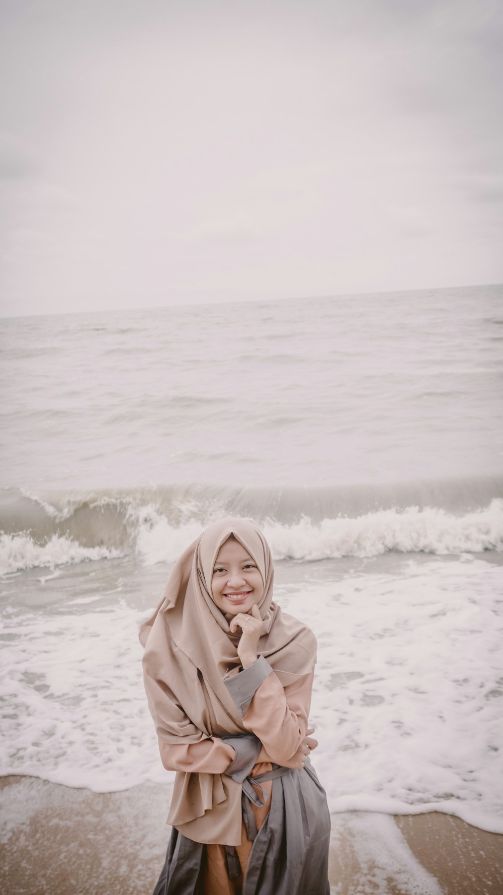 donna che indossa hijab marrone accanto alla riva del mare