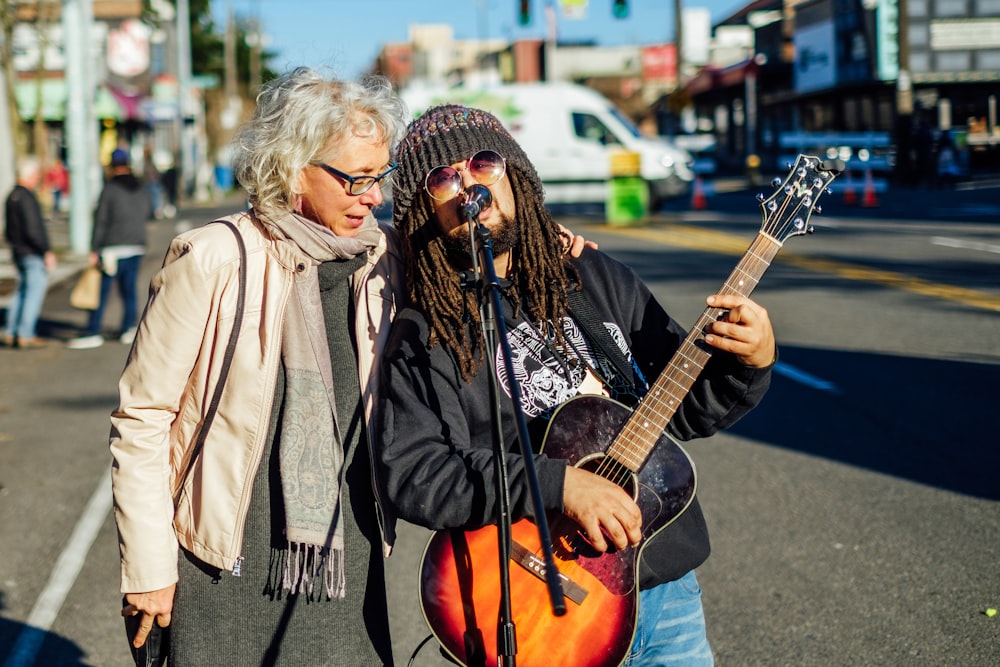 man singing on the street while playing guitar