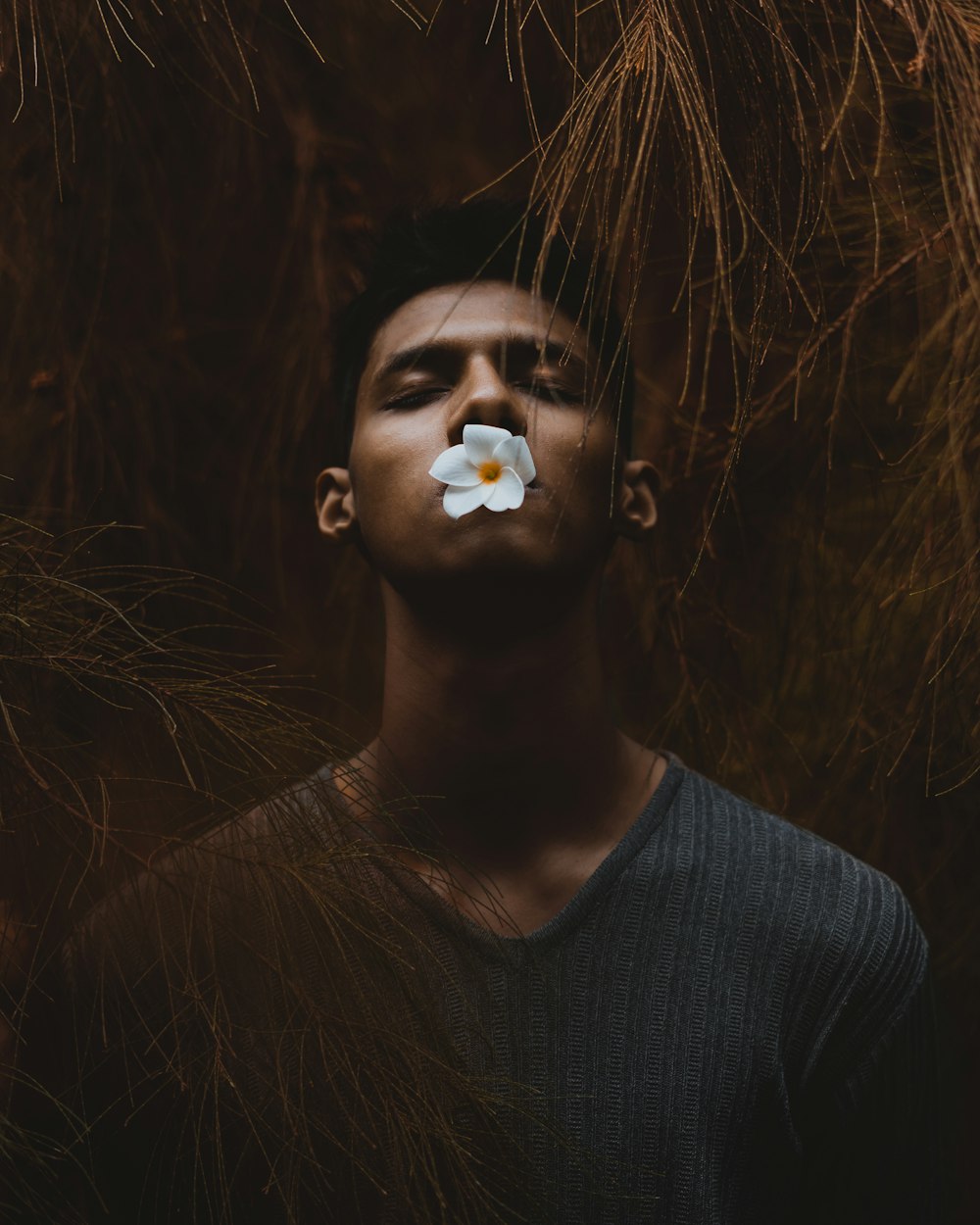 man holding white flower with his lips