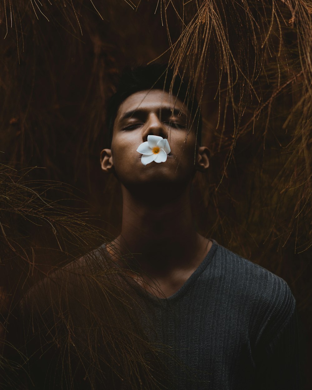 hombre sosteniendo una flor blanca con sus labios